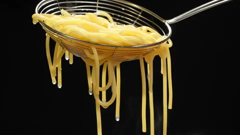 Draining Cooked Spaghetti in Wire Skimmer on Black Video stock 345773243