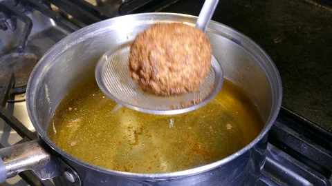 Draining a deep fried Scotch egg from a pan of boiling oil. Video stock 102219043