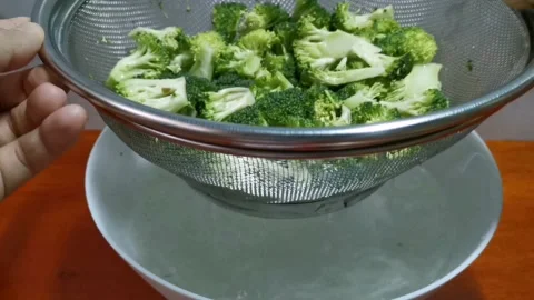 Draining Excess Water of Broccoli Florets in a Strainer Stock Footage 234882872