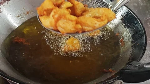 Draining golden crispy fried fish on a strainer over a pan. Stock Footage 342690553