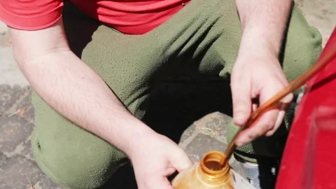Draining hot old engine oil from a car through a tube at home. Oil change, v Stock Footage 335260357