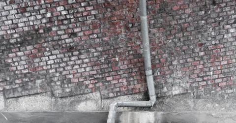 A drainpipe for rain in front of a brick wall Stock Photos
