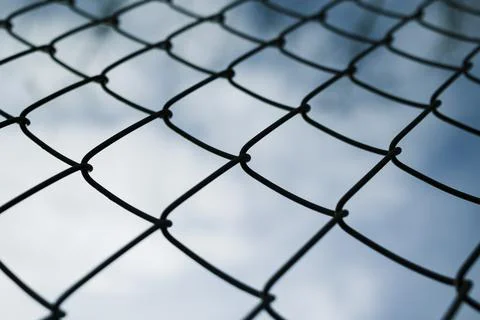 Dramaic blue sky with white clouds through a metal grid chain fence . low a.. Stock Photos