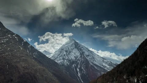 Dramatic 4K Aerial View of Snow-Capped Mountain Peaks Under Cloudy Sky Stock Footage 329199801