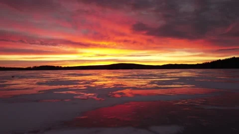 Dramatic 4k Drone Aerial Vibrant Sunrise Sky Reflecting Over Swedish Frozen Lake Stockbeeldmateriaal 235689473