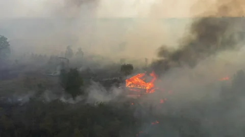 Dramatic Aerial of Burning House Amongst Peat Fire, Indonesia Stock Footage 142510824