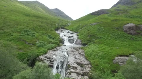 Dramatic aerial / drone shot in Glencoe along a river in the Scottish highlands Stock Footage