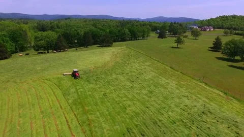 A dramatic aerial of a framer cutting a hayfield Stock Footage 337204525