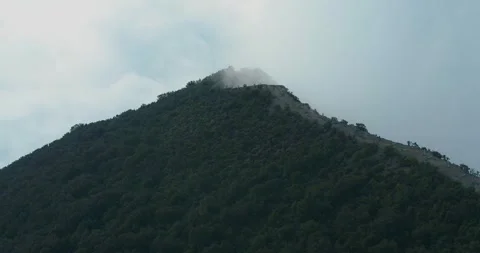 Dramatic Aerial of Mountain Peak Emerging Through Fog at Sunset Indonesia 動画素材 331708195