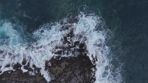 A dramatic aerial perspective captures powerful ocean waves crashing over dark Stock Footage 336123866