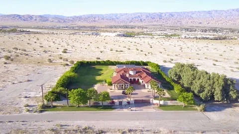 A dramatic aerial reveals a large mansion in miles of lonely desert. Video stock 79404722