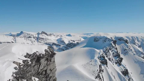 Dramatic aerial shot of athlete on a summit with skies Stock Footage 99739801