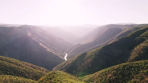 Dramatic Aerial shot over valley with river far below. Shot at sunrise. Video stock 228647790