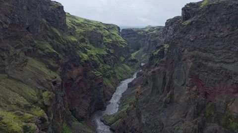 Dramatic aerial sweep over a deep Icelandic gorge and rushing glacial stream. 스톡 동영상 327511362
