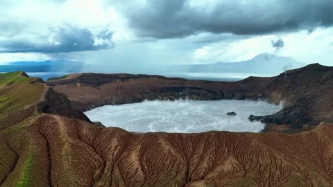 Dramatic aerial view of active volcano with steaming crater lake under clouds Stock-Footage 341388591