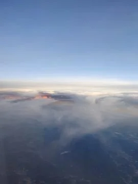 A dramatic aerial view from an airplane window featuring sunlit cloud tops with  写真素材
