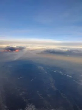A dramatic aerial view from an airplane window featuring sunlit cloud tops with  写真素材