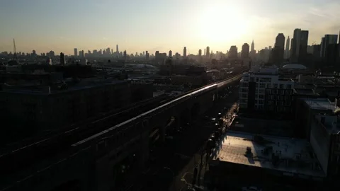 A dramatic aerial view of an elevated subway train at sunset, with the Stock Footage 237444494