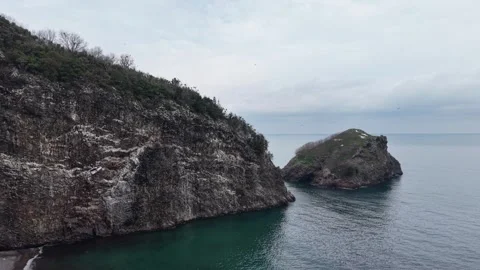Dramatic Aerial View of Isolated Rocky Island Under Dark Cloudy Sky Vídeo Stock 334247063