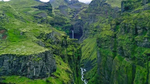 Dramatic aerial view of lush green canyon with scenic waterfalls flowing down Stock Footage 343696241