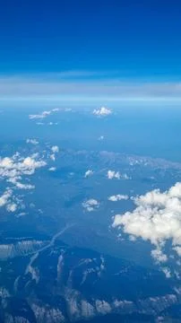 Dramatic aerial view of mountain ridges and scattered clouds captured from airpl Fotos Stock