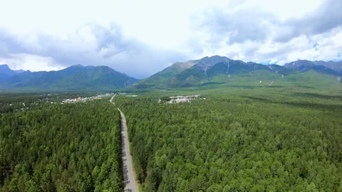 Dramatic aerial view of mountains, green forest landscape, road and town Stock Footage 92339193