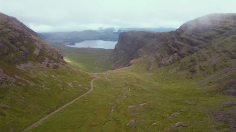 Dramatic aerial view of Scotland's green valley with mountains and serene lake Stock Footage 297868893
