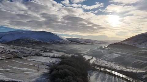 Dramatic aerial view of snow-covered mountains and valleys under a cloudy sky. Stock Footage 297663842