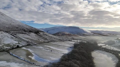 Dramatic aerial view of snow-covered mountains and valleys under a cloudy sky. Stock Footage 297710840