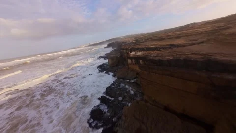 Dramatic aerial view of stormy ocean meeting jagged coastlines Stock Footage 344677904