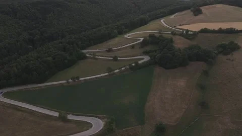 A dramatic aerial view of a winding country road weaving through rolling Stock Footage 339382418