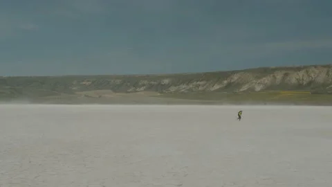 Dramatic aerial of young boy running in Utah desert salt flat Stock Footage 159872155