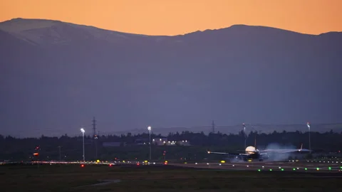 Dramatic Airplane Landing at Twilight with Mountain Backdrop Видео 332457372