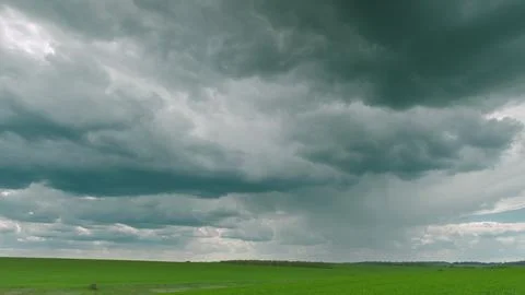 Dramatic and Captivating Clouds Gracefully Floating Over a Vibrant Green Landsca Stockfoto's