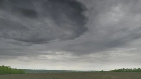 A Dramatic and Cloudy Sky Sprawls Over a Vast and Barren Field Stretching to the Fotos Stock