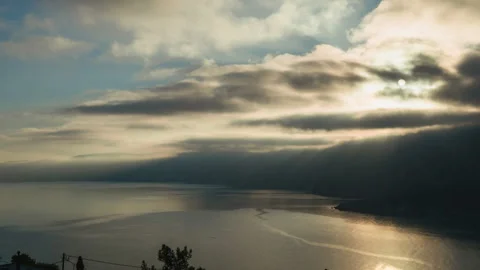 Dramatic and moody time lapse shot of sunrise over rocky shore and calm sea on Stock Footage 341467904
