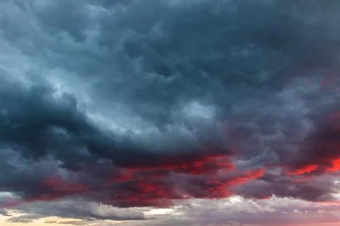 Dramatic and spectacular gray and red clouds illuminated by sunset or sunrise Stock Photos