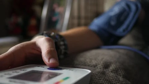 Dramatic angle of woman checking her blood pressure on couch Stock Footage 291552176