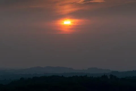 Dramatic apocalyptic sinister scene of bright orange sun behind clouds over s Stock Photos