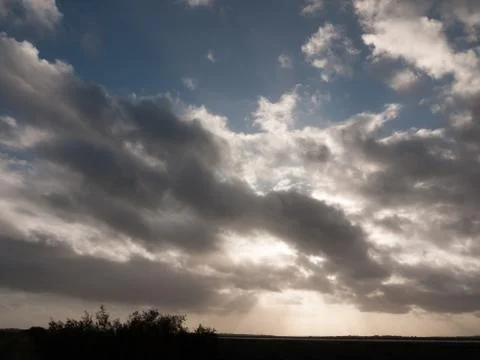 Dramatic autumn grey stormy clouds with sun beams over coastal grass landscap Foto stock
