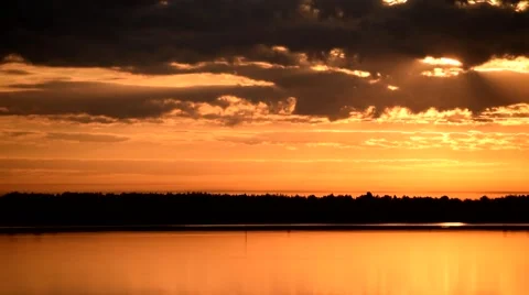 Dramatic backlit orange and yellow clouds move over water Stock Footage 68748379
