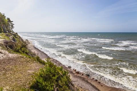 Dramatic Baltic Sea cliff coast with foamy waves and blue sky Stock Photos