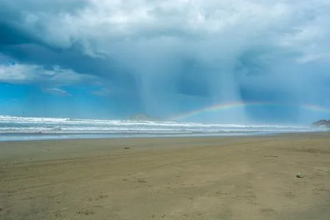 Dramatic Beach Scene with Rainbow and Rain Showers Fotos Stock