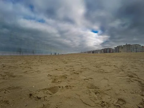 Dramatic Beach Scene with Reflections and Residential Buildings under Overc.. Stock Photos