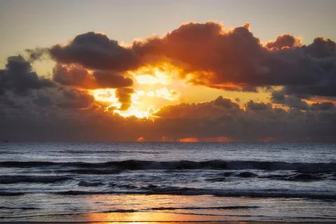 Dramatic Beach Sunset Behind Clouds Stock Photos