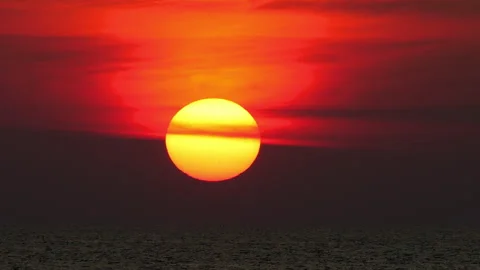 Dramatic big sun setting over the ocean against a vibrant red sky. Stock Footage 335756220