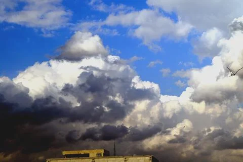 Dramatic billowing cumulus storm clouds rolling over a building rooftop against Stock Photos