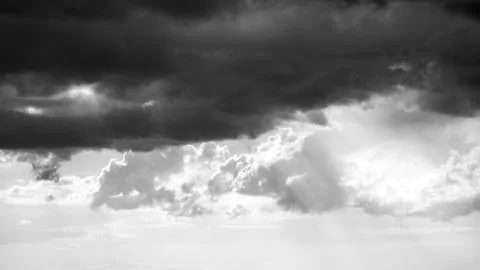Dramatic black and white cloudscape with light rays, ideal for text overlay. Stock Photos