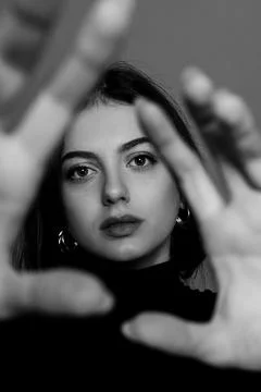 Dramatic black and white portrait of young woman looking through her hands Stock Photos