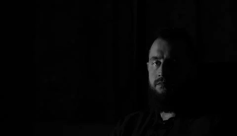 Dramatic black and white portrait of a bearded man in deep shadow with inte.. Stock Photos